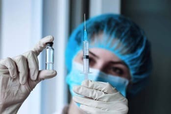 Услуги по снятию ломки в стационаре Врач в медицинской маске держит в руке лекарство и шприц